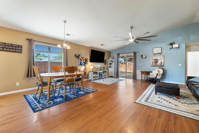 dining area with vaulted ceiling, a chandelier, light wood-style floors, ceiling fan, and baseboards