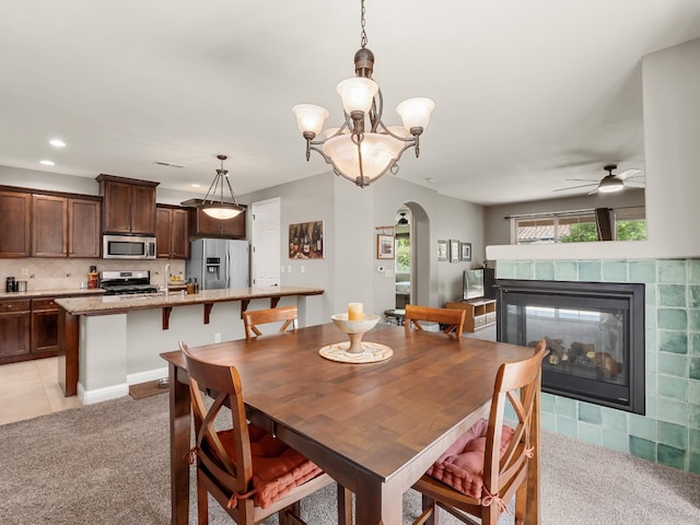 11340 N Via Milano Way, Fresno, CA 93730 - dining area featuring arched walkways, light colored carpet, ceiling fan, a tiled fireplace, and recessed lighting