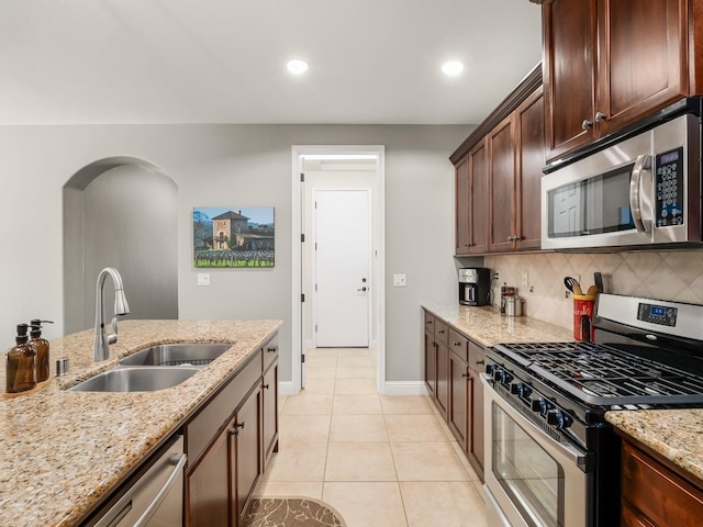 11340 N Via Milano Way, Fresno, CA 93730 - kitchen with appliances with stainless steel finishes, a sink, backsplash, baseboards, and light stone countertops