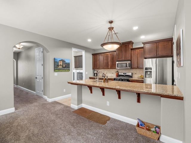 11340 N Via Milano Way, Fresno, CA 93730 - kitchen with appliances with stainless steel finishes, light carpet, arched walkways, a kitchen bar, and light stone countertops