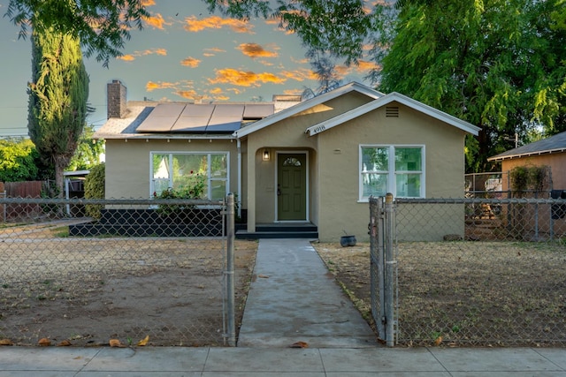 4918 E Illinois Ave, Fresno, CA 93727 - bungalow with stucco siding, roof mounted solar panels, a chimney, and a fenced front yard