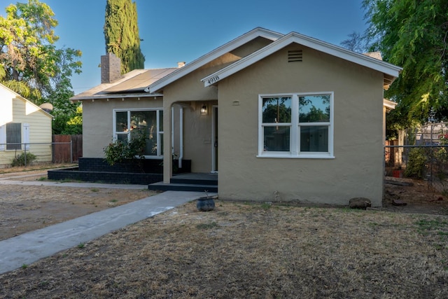 4918 E Illinois Ave, Fresno, CA 93727 - bungalow with a chimney, stucco siding, and roof mounted solar panels