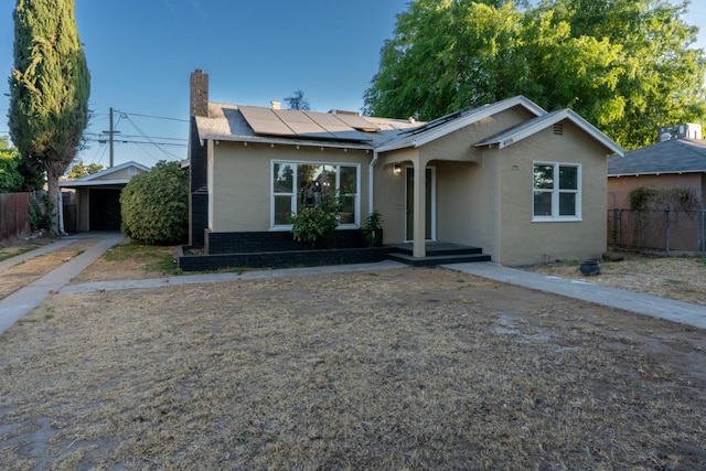 4918 E Illinois Ave, Fresno, CA 93727 - view of front of house featuring stucco siding, roof mounted solar panels, and a chimney