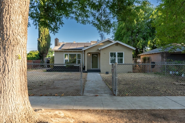 4918 E Illinois Ave, Fresno, CA 93727 - view of front of house featuring roof mounted solar panels, a fenced front yard, a gate, stucco siding, and a chimney