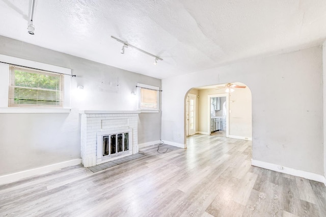 1934 N Vagedes Ave, Fresno, CA 93705 - unfurnished living room featuring rail lighting, arched walkways, a textured ceiling, wood finished floors, and plenty of natural light