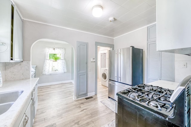 1934 N Vagedes Ave, Fresno, CA 93705 - kitchen featuring gas range oven, freestanding refrigerator, washer / clothes dryer, arched walkways, and light wood finished floors