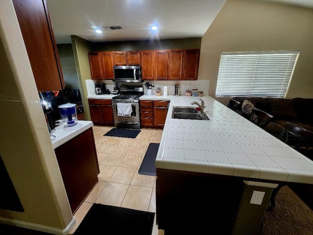5788 E Mono St, Fresno, CA 93727 - kitchen featuring stainless steel appliances, a sink, tile counters, a peninsula, and light tile patterned floors