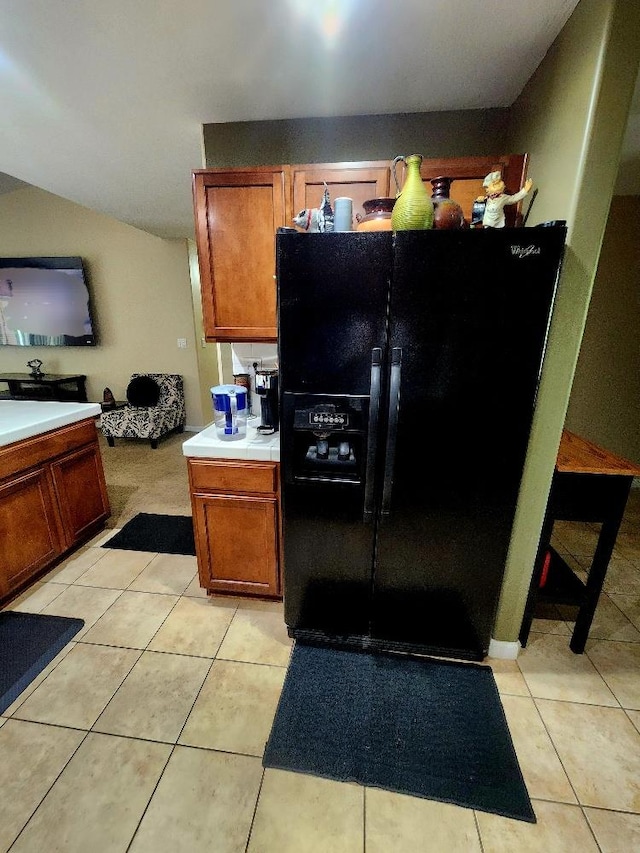 5788 E Mono St, Fresno, CA 93727 - kitchen with black fridge, light tile patterned flooring, brown cabinetry, and tile countertops