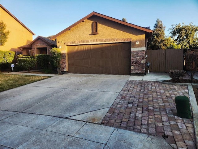 5788 E Mono St, Fresno, CA 93727 - view of front of house featuring an attached garage, driveway, stone siding, and stucco siding