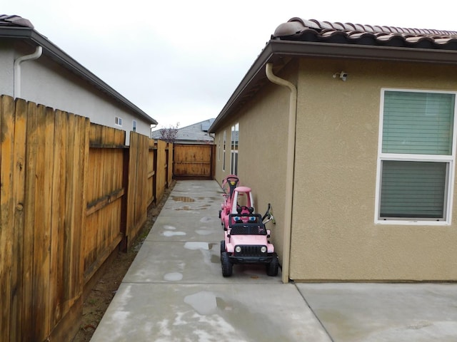 865 S Bridle Ave, Fresno, CA 93727 - view of side of home with stucco siding, a patio area, and a tile roof
