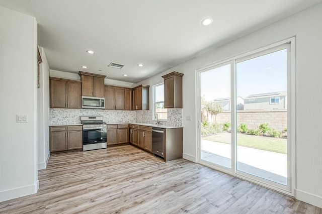 1175 Maclure Ave W, Madera, CA 93636 - kitchen featuring appliances with stainless steel finishes, backsplash, light wood finished floors, light countertops, and baseboards