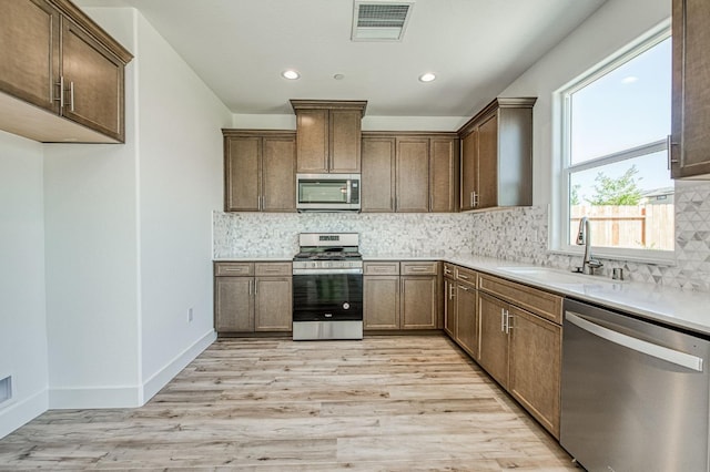1175 Maclure Ave W, Madera, CA 93636 - kitchen with stainless steel appliances, a sink, light wood-style floors, tasteful backsplash, and recessed lighting