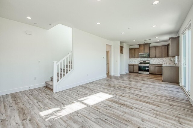 1175 Maclure Ave W, Madera, CA 93636 - unfurnished living room featuring recessed lighting, light wood-style floors, stairway, a sink, and baseboards