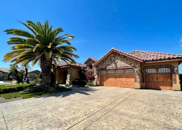 16052 W Middleton Ave, Kerman, CA 93630 - mediterranean / spanish house with a tile roof, an attached garage, decorative driveway, stucco siding, and stone siding