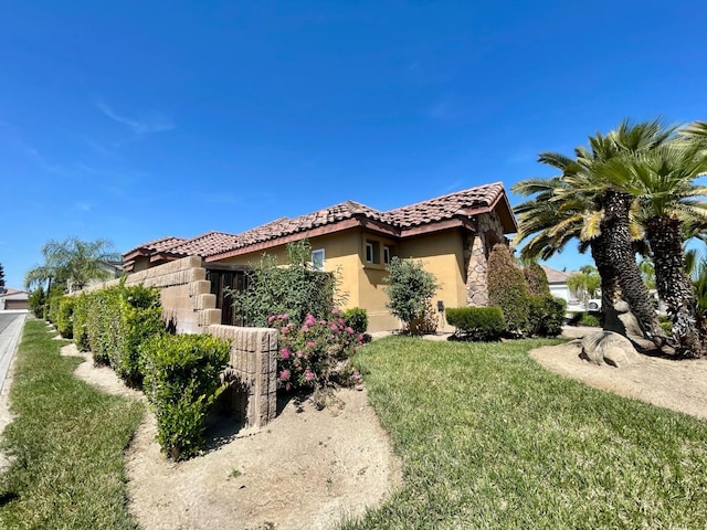 16052 W Middleton Ave, Kerman, CA 93630 - view of home's exterior featuring stucco siding, a tiled roof, an attached garage, and a lawn