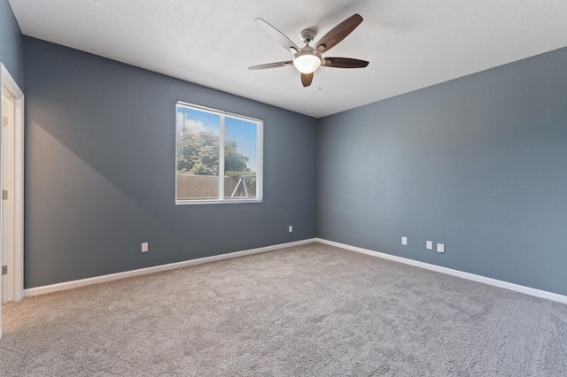 carpeted empty room with ceiling fan and baseboards
