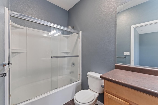 bathroom with a textured wall, toilet, shower / bath combination with glass door, and vanity