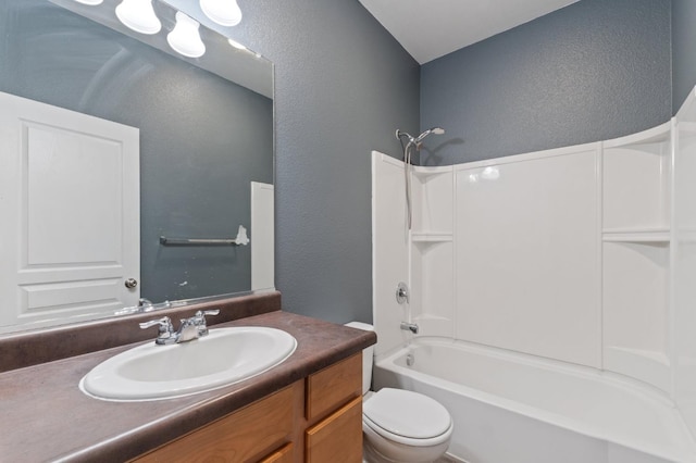 bathroom featuring bathing tub / shower combination, toilet, a textured wall, and vanity
