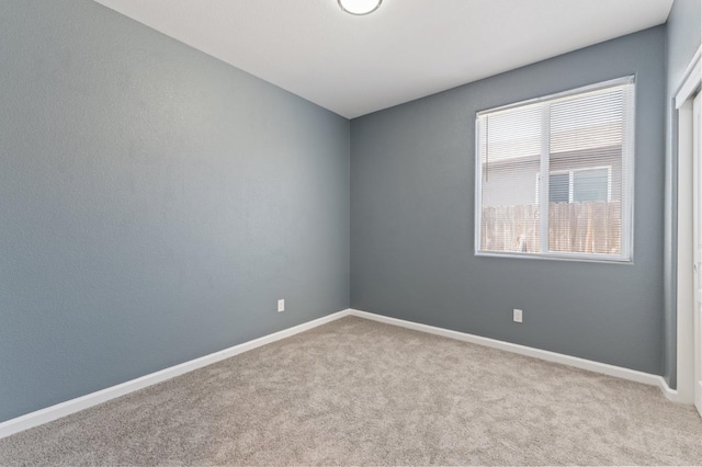 carpeted spare room featuring baseboards