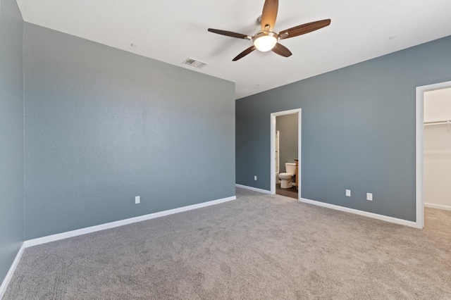 unfurnished bedroom featuring a walk in closet, carpet floors, baseboards, a closet, and connected bathroom