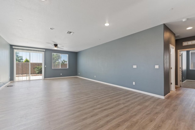 unfurnished living room with light wood-style flooring, a ceiling fan, and baseboards