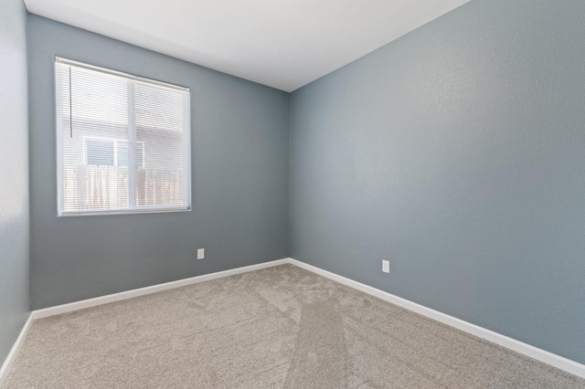 unfurnished room featuring carpet and baseboards