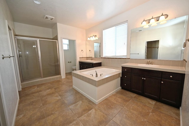 bathroom with toilet, a stall shower, a garden tub, vanity, and baseboards