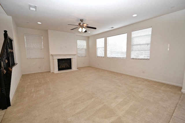 unfurnished living room with a ceiling fan, a glass covered fireplace, light carpet, baseboards, and recessed lighting