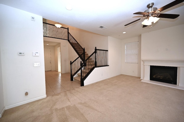 unfurnished living room featuring light carpet, a ceiling fan, stairway, a glass covered fireplace, and recessed lighting