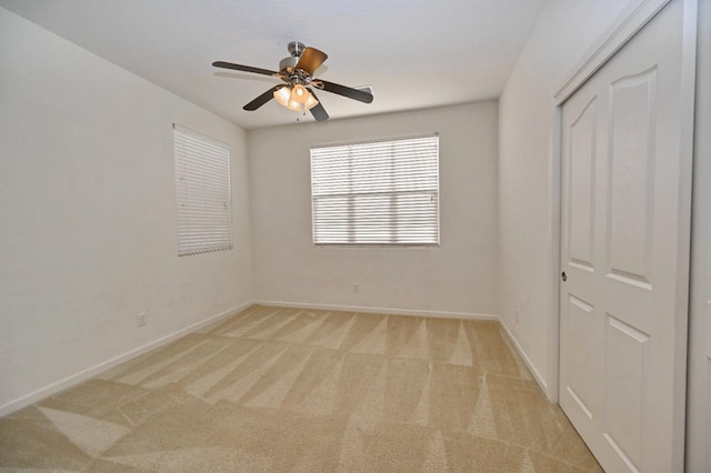 unfurnished bedroom with baseboards, light colored carpet, a closet, and ceiling fan