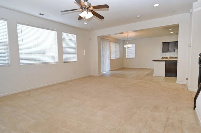 empty room featuring light carpet, a chandelier, a ceiling fan, baseboards, and recessed lighting