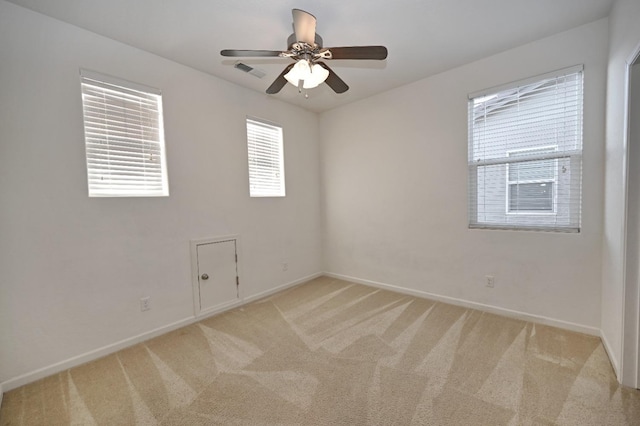 spare room featuring light colored carpet, baseboards, and ceiling fan
