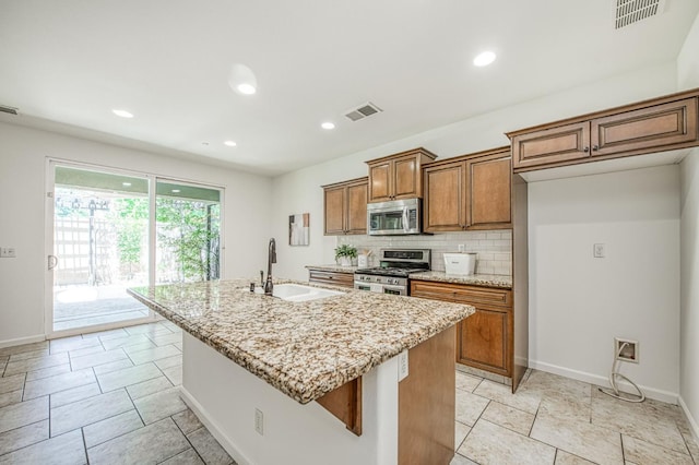 kitchen featuring stainless steel appliances, brown cabinets, decorative backsplash, light stone counters, and recessed lighting