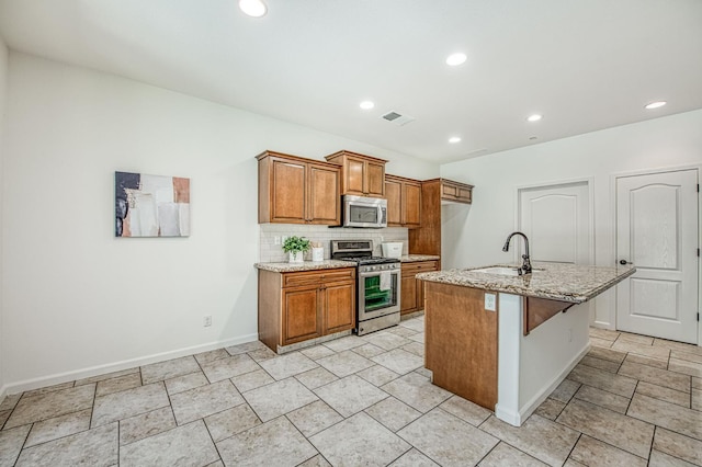 kitchen with stainless steel appliances, a sink, brown cabinetry, backsplash, and baseboards