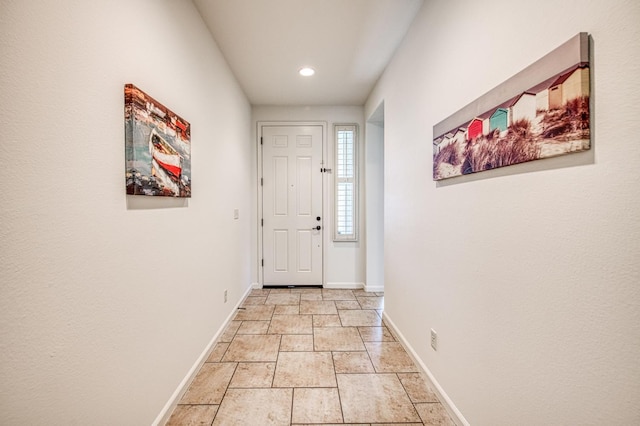 doorway to outside featuring baseboards, stone tile floors, and recessed lighting