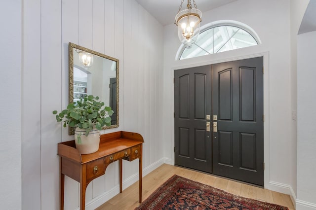 entrance foyer with wood finished floors, a chandelier, and baseboards