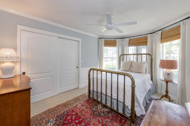 bedroom with carpet floors, ornamental molding, wainscoting, a closet, and ceiling fan