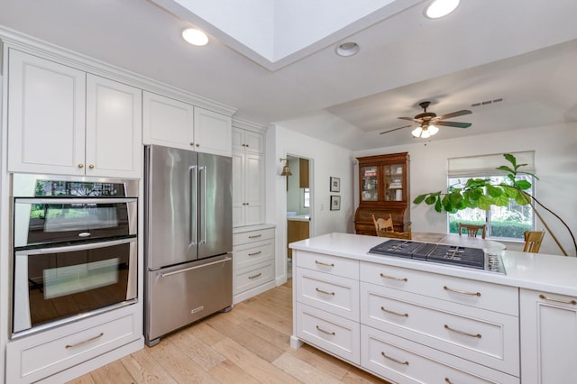 kitchen featuring appliances with stainless steel finishes, light wood-type flooring, light countertops, white cabinetry, and a ceiling fan