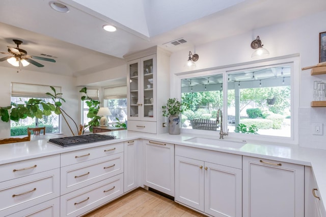 kitchen featuring a sink, stainless steel gas stovetop, light countertops, white cabinets, and a ceiling fan