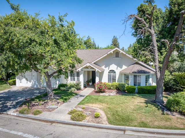 view of front of home with a front lawn, concrete driveway, a garage, and a shingled roof