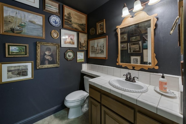 half bathroom with vanity, toilet, and baseboards