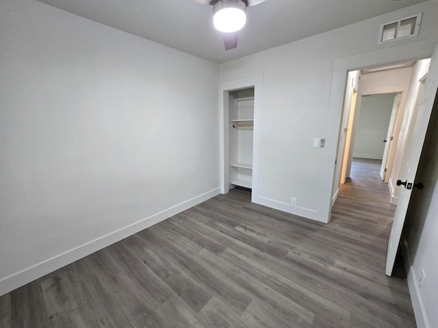 unfurnished bedroom featuring dark wood-style flooring, baseboards, a closet, and ceiling fan