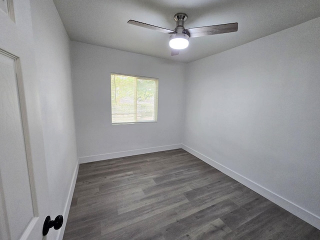 spare room featuring a ceiling fan, baseboards, and dark wood-type flooring