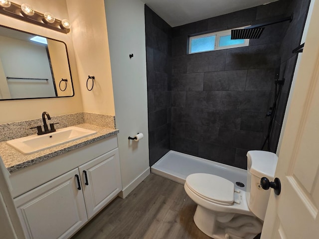 full bath featuring wood finished floors, vanity, toilet, and a tile shower