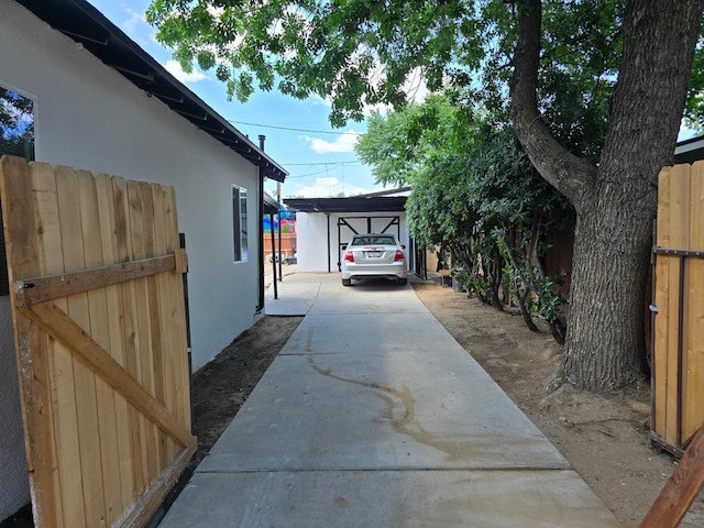 view of side of property featuring stucco siding, a carport, and concrete driveway
