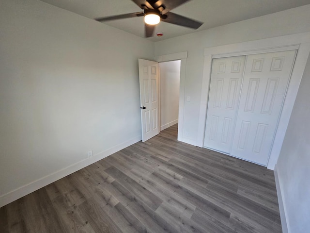 unfurnished bedroom with baseboards, wood finished floors, a closet, and a ceiling fan