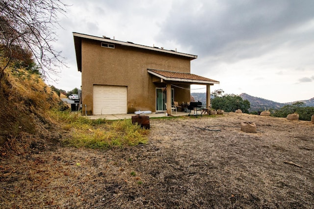 45704 Butternut Ln, Yokuts Valley, CA 93675 - back of property featuring stucco siding, a patio area, a garage, and a mountain view