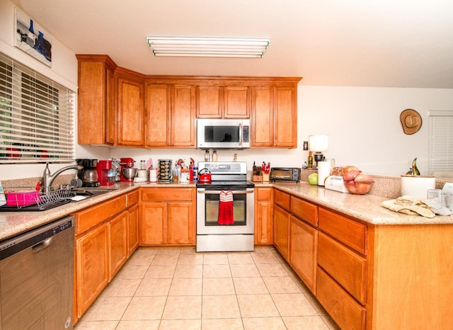 45704 Butternut Ln, Yokuts Valley, CA 93675 - kitchen with appliances with stainless steel finishes, a peninsula, a sink, light tile patterned flooring, and brown cabinetry