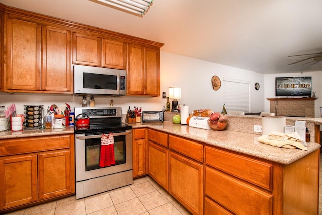 45704 Butternut Ln, Yokuts Valley, CA 93675 - kitchen with stainless steel appliances, a peninsula, brown cabinetry, and light tile patterned floors