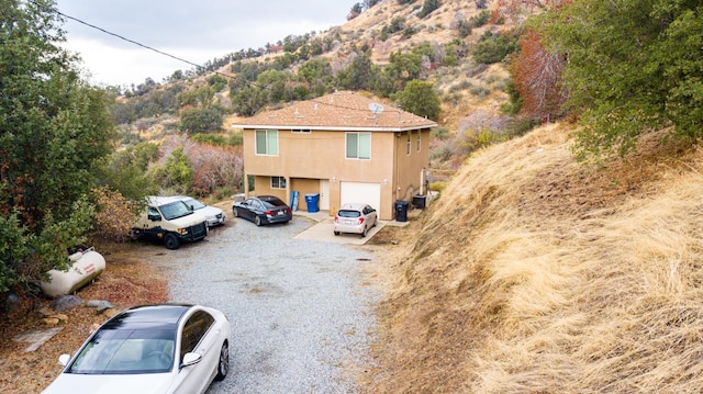 45704 Butternut Ln, Yokuts Valley, CA 93675 - view of front of home with stucco siding, gravel driveway, a mountain view, and an attached garage